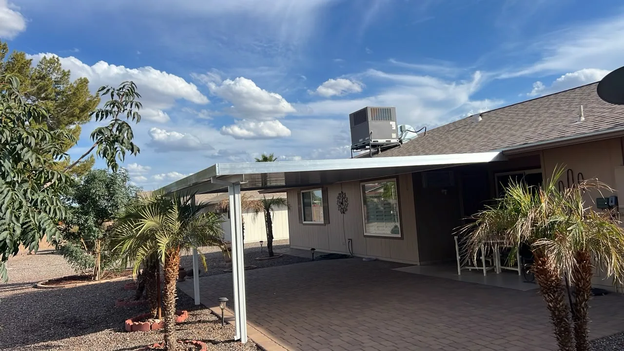 Attached carport cover extending over a driveway beside a garage